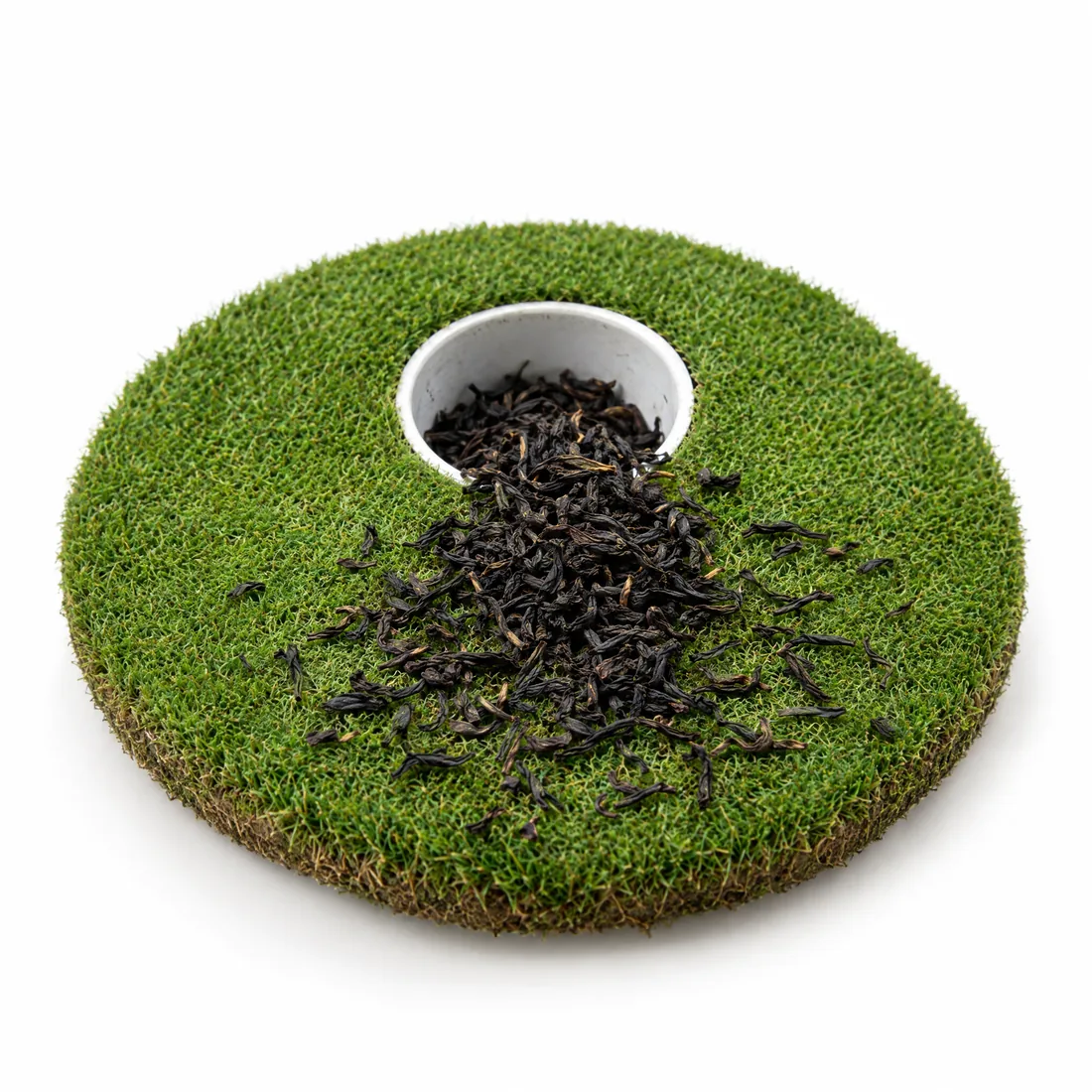 Loose black tea leaves spilling out of a golf hole cup